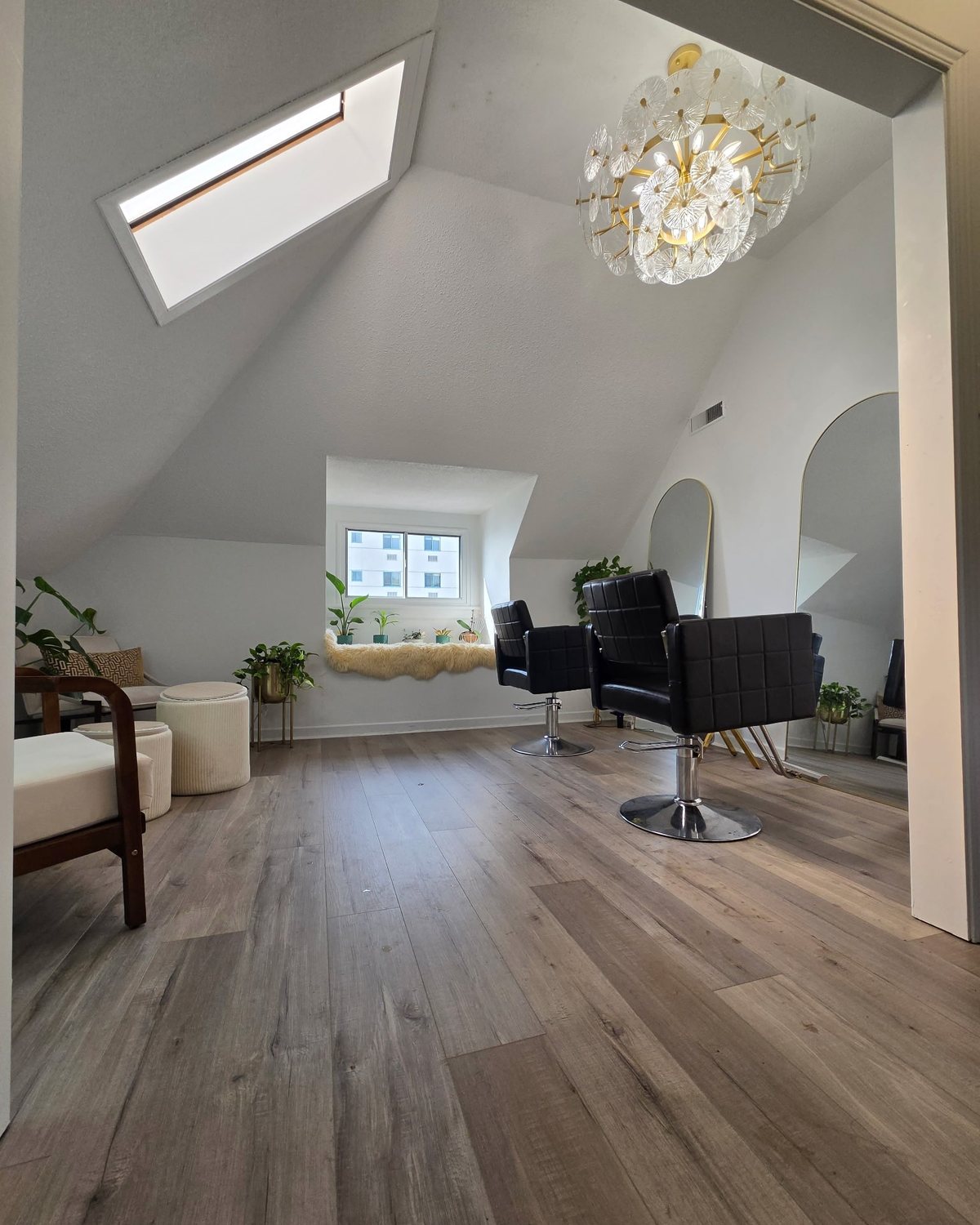 Inside the Marc David Hair studio: styling chairs, arched mirrors, a window seat and a chandelier under the skylight